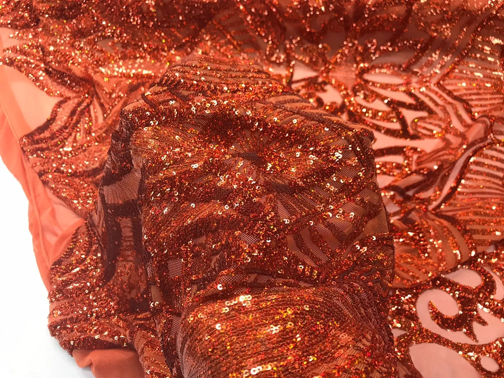 Burnt orange iridescent shiny sequin royalty design on a 4 way stretch mesh-sold by the yard.