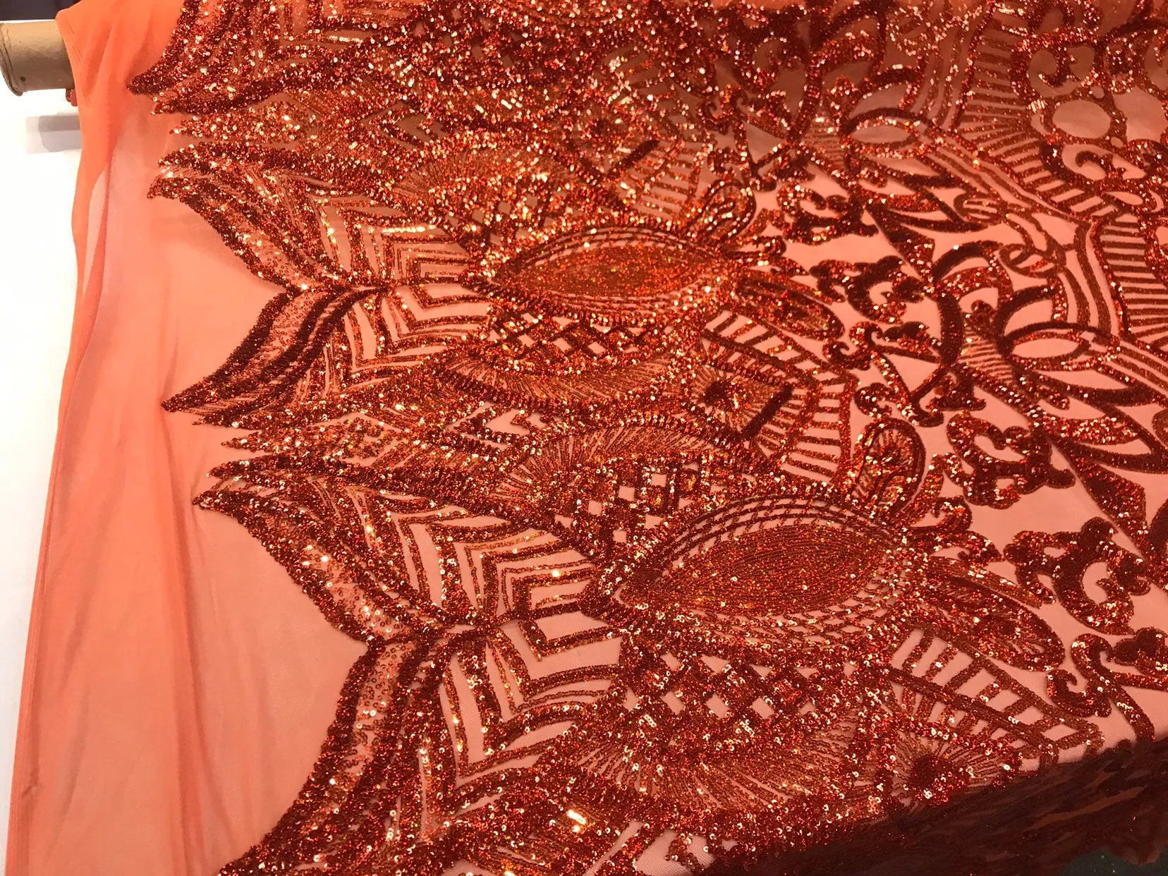 Burnt orange iridescent shiny sequin royalty design on a 4 way stretch mesh-sold by the yard.