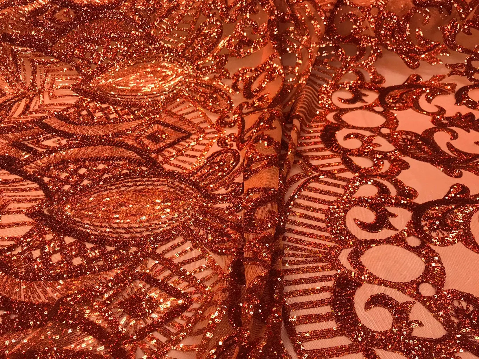 Burnt orange iridescent shiny sequin royalty design on a 4 way stretch mesh-sold by the yard.